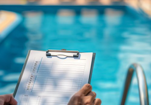 A pool service professional reviews a checklist by the poolside to ensure proper maintenance and safety checks for optimal care and user safety